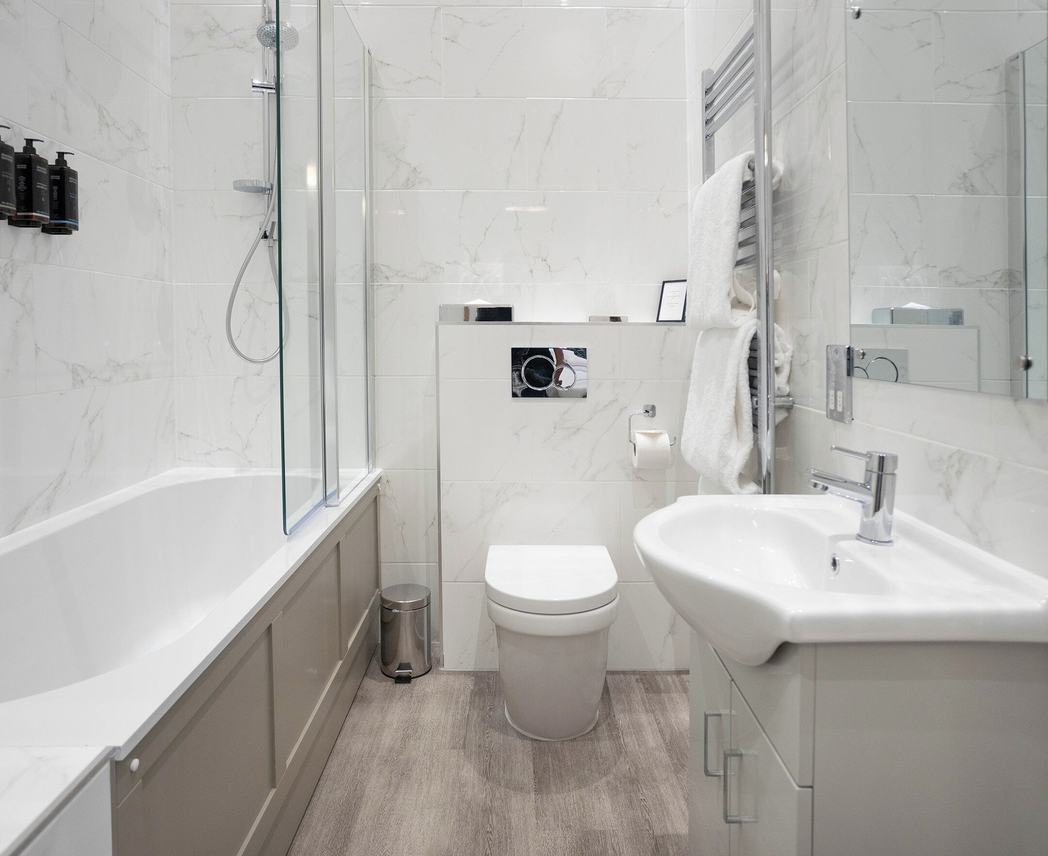 A modern bathroom with a glass shower enclosure, a white toilet, and a sink with a mirror.