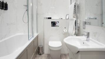 A modern bathroom with a glass shower enclosure, a white toilet, and a sink with a mirror.