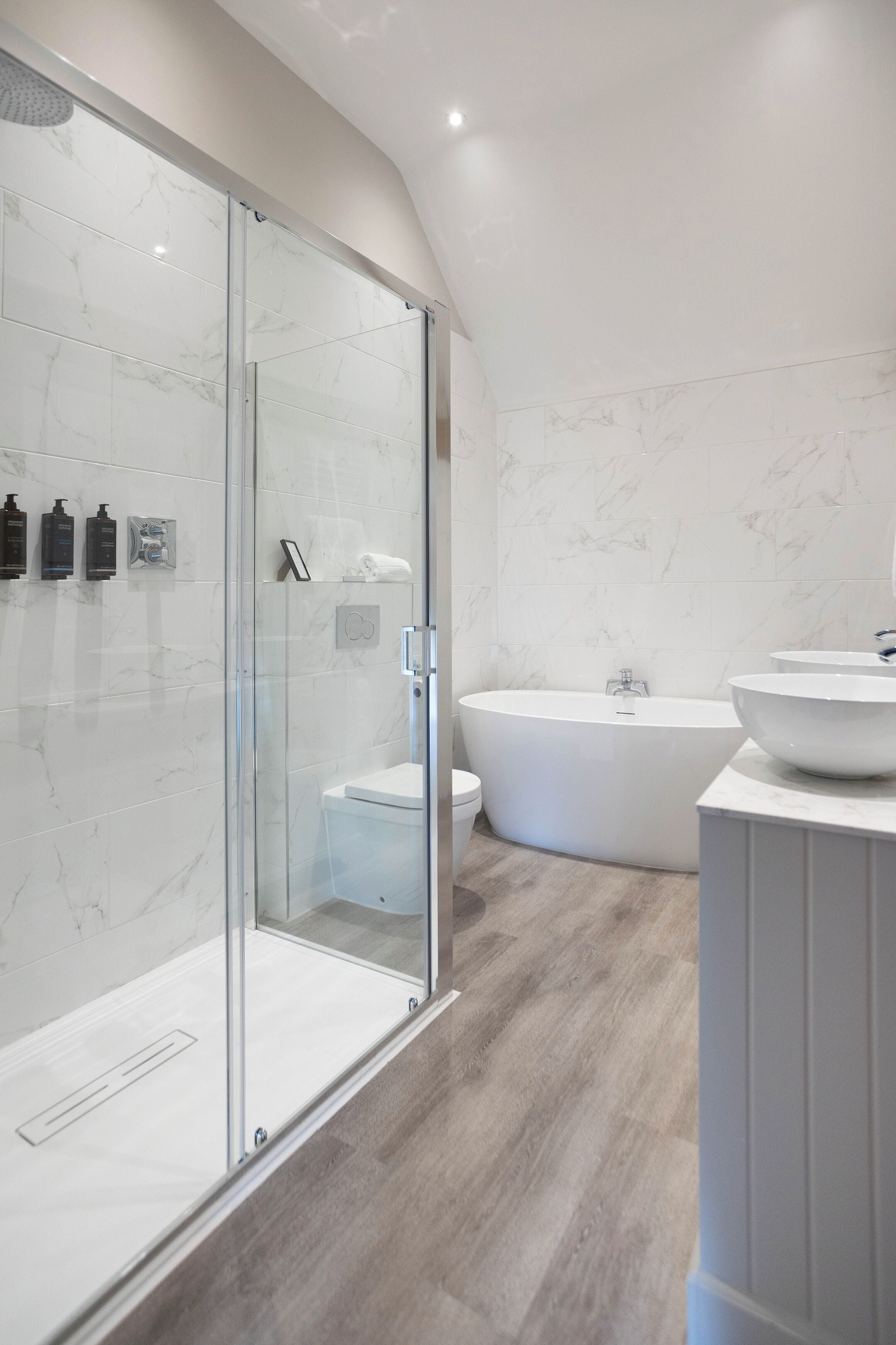 A modern bathroom with a glass-enclosed shower, a freestanding bathtub, and a vanity with a large bowl sink.
