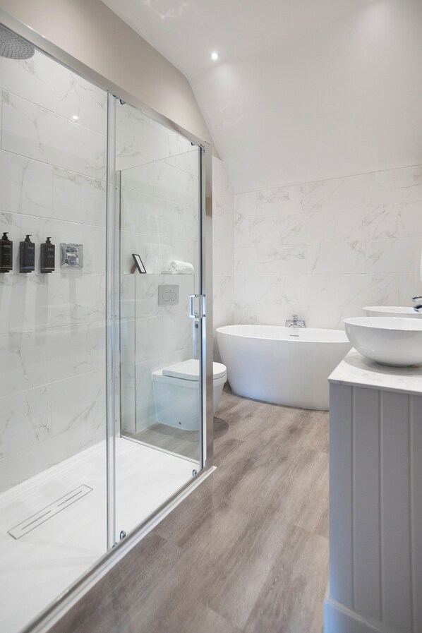 A modern bathroom with a glass-enclosed shower, a freestanding bathtub, and a vanity with a large bowl sink. - Barton Hall Hotel & Spa (Kettering)