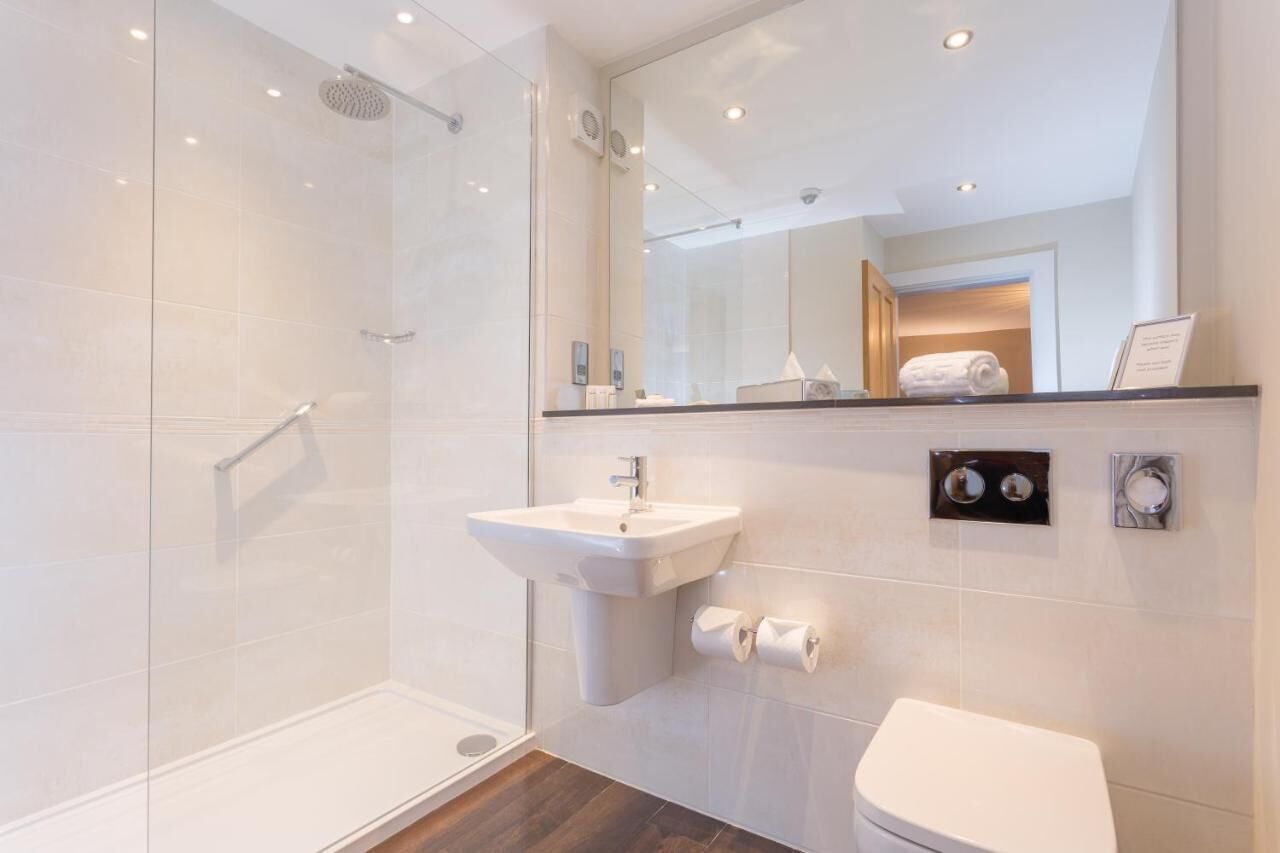 A modern bathroom with a glass shower enclosure, a white sink, and a toilet.