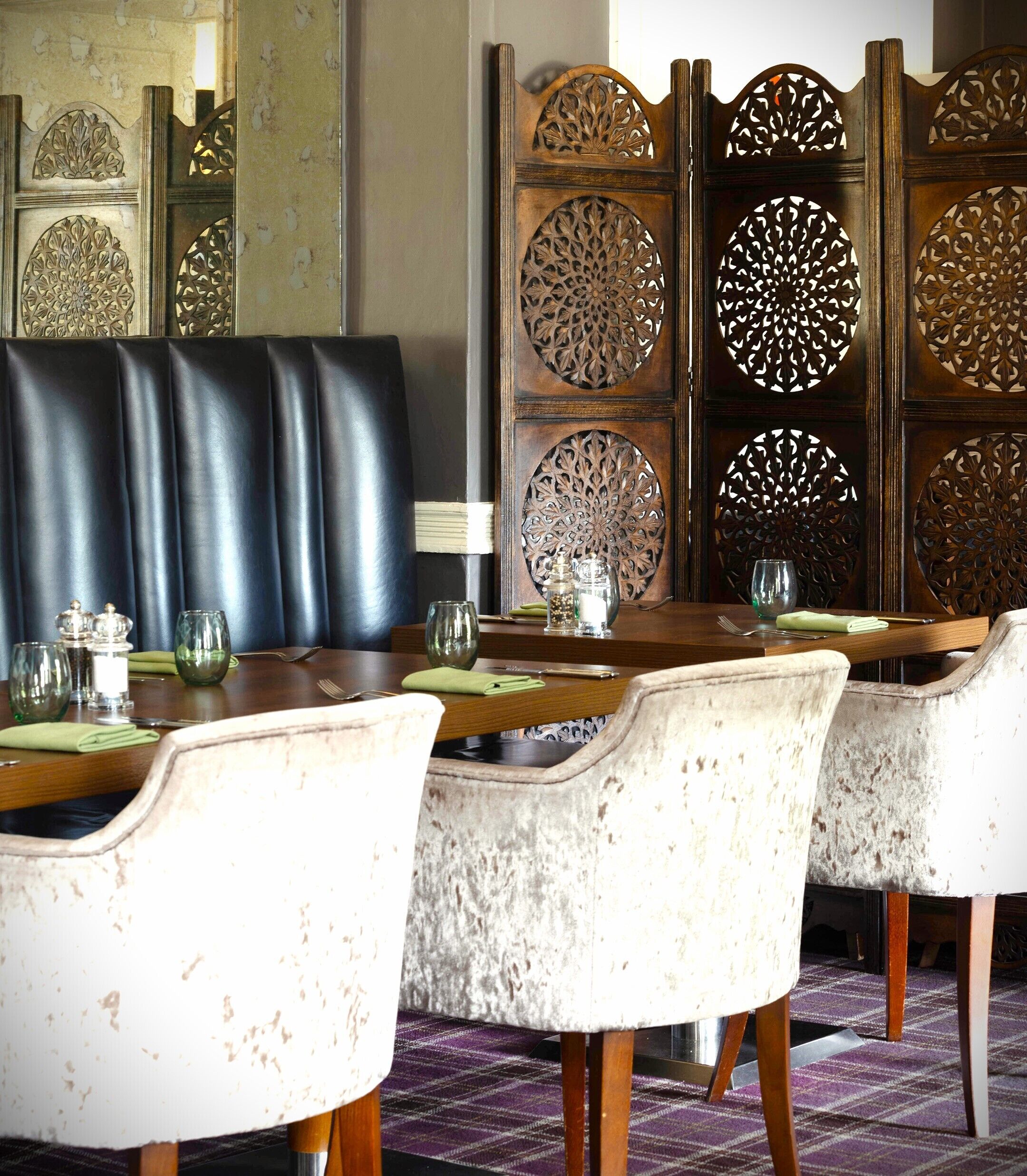 Un comedor con sillas de cuero, una mesa de madera y un panel decorativo con diseños elaborados.