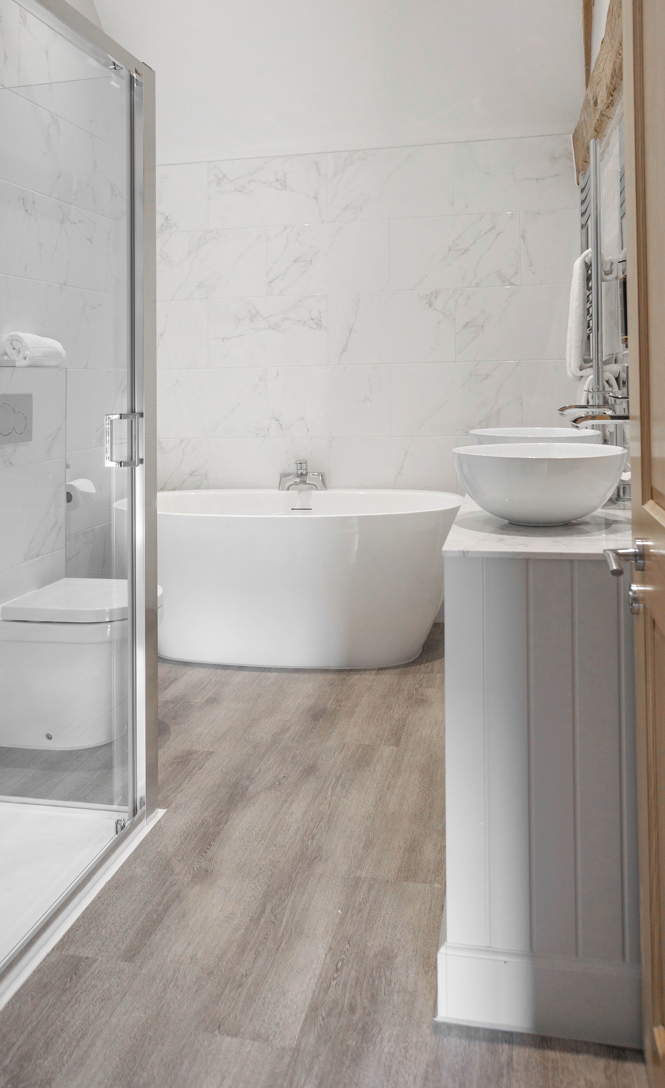 A modern bathroom with a glass shower enclosure, a freestanding bathtub, and a vanity with a large basin.
