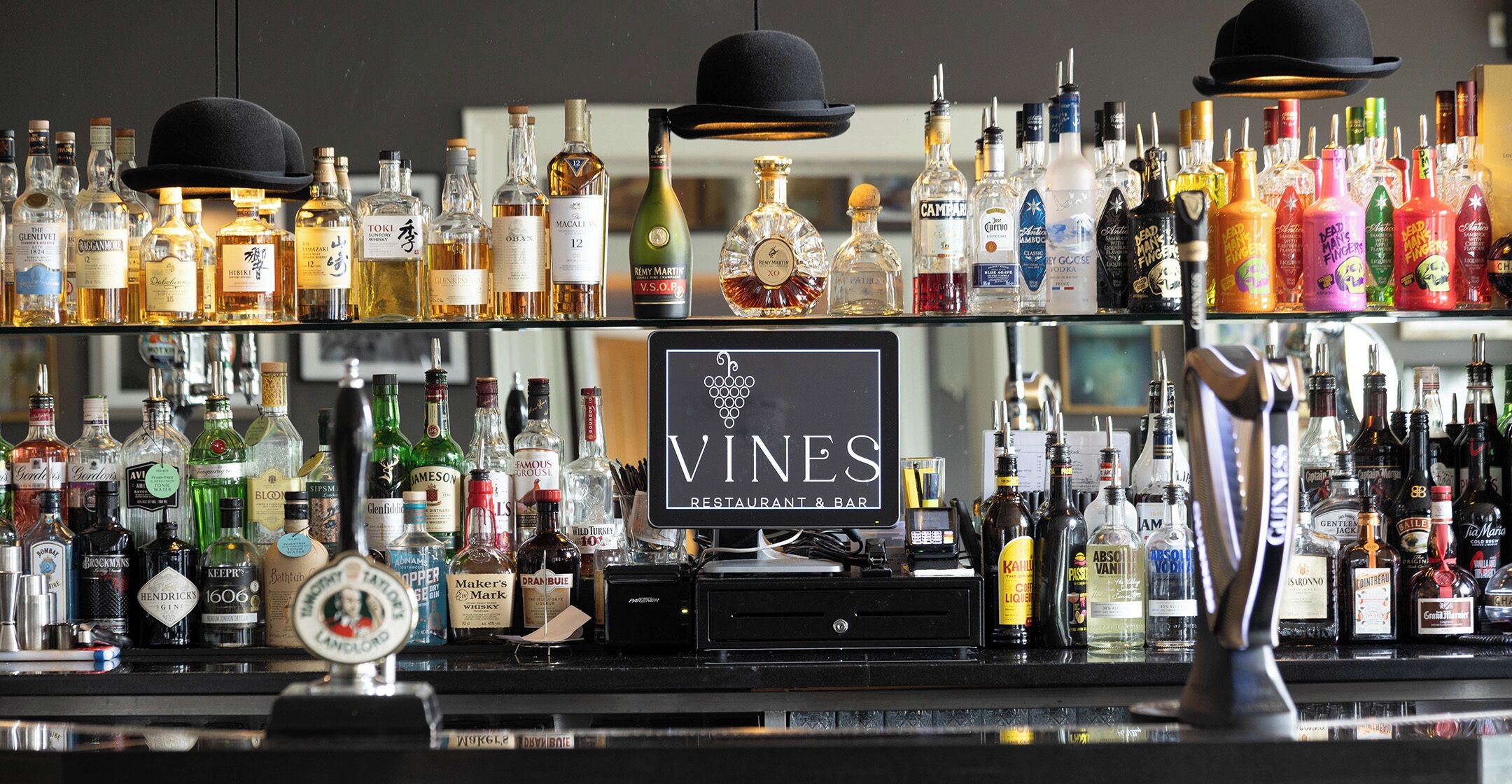 A bar with a variety of liquor bottles and a sign that reads "VINES RESTAURANT & BAR".