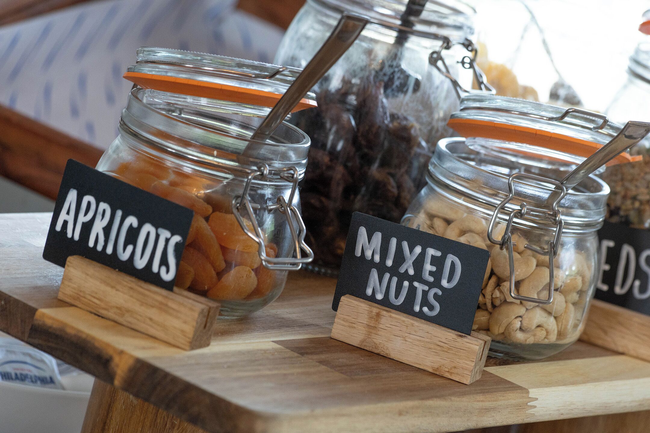 Une table en bois sur laquelle sont posés deux bocaux étiquetés « abricots » et « mélange de noix ».