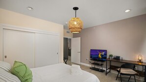 Ein Schlafzimmer mit einem Bett, einem Schreibtisch, einem Fernseher und einem Stuhl.