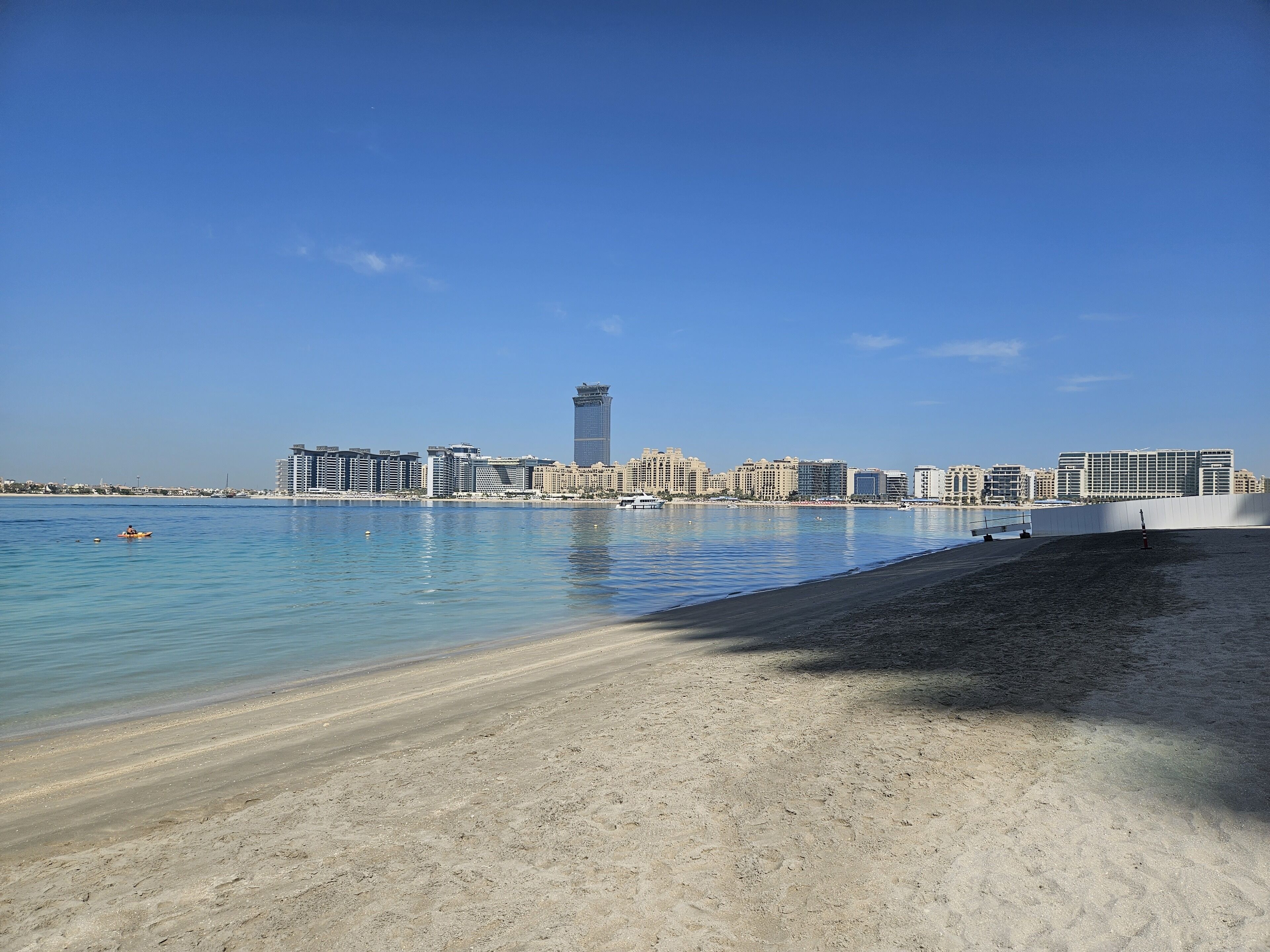 Una playa con una vista despejada de un horizonte urbano al fondo.