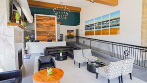 Un vestíbulo de hotel con una recepción, zona de estar y un gran mural de una playa.