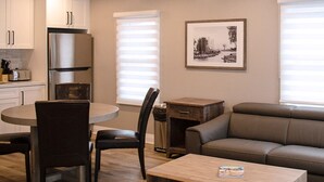 Una cocina moderna con armarios blancos, un refrigerador de acero inoxidable y un comedor con una mesa redonda y sillas.