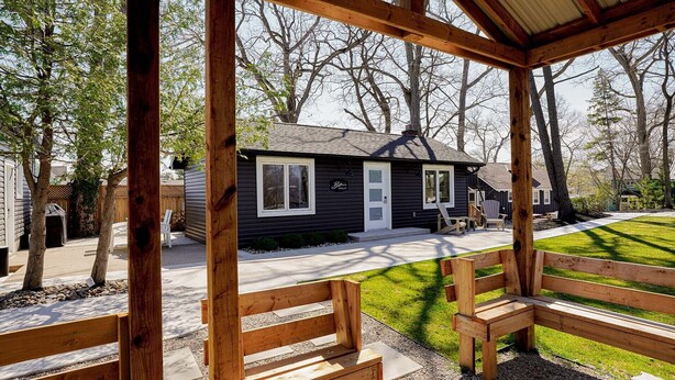 Un pabellón de madera con bancos, una casita de aspecto oscuro con detalles blancos y un letrero que dice "Belfry Chalet".