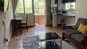 Un salon comprenant un canapé, une table basse, un téléviseur et un coin cuisine avec un réfrigérateur et un four à micro-ondes.