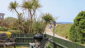A patio with a grill, a chair, and a view of the sea. - Kingsholm (Truro)