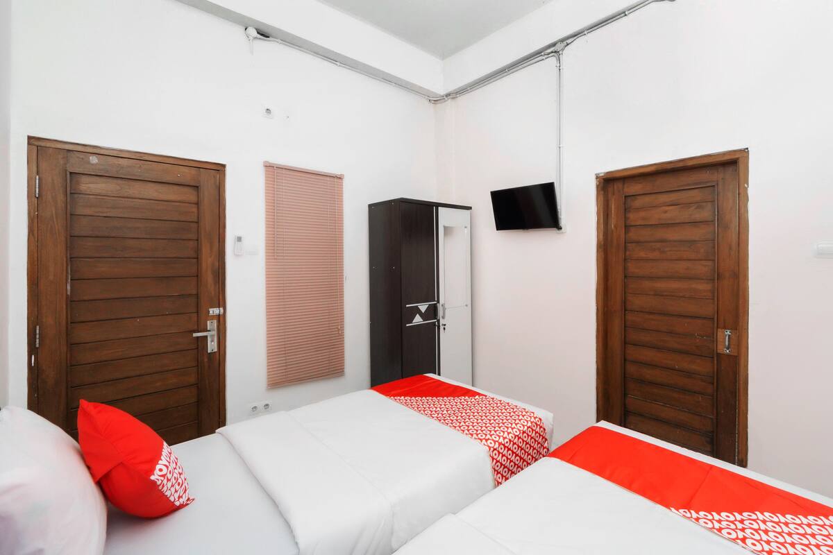 A room with two beds, a wardrobe, and a TV.