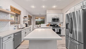 Una cocina moderna con armarios blancos, electrodomésticos de acero inoxidable y una isla central.
