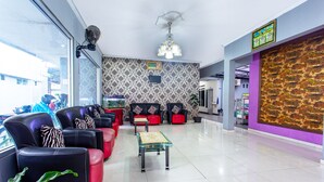 A lobby with leather sofas, a glass coffee table, and a patterned wall.