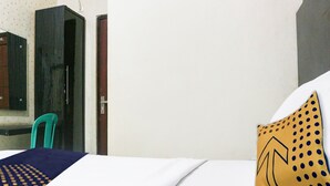 A hotel room with a bed, a chair, a mirror, and a door.