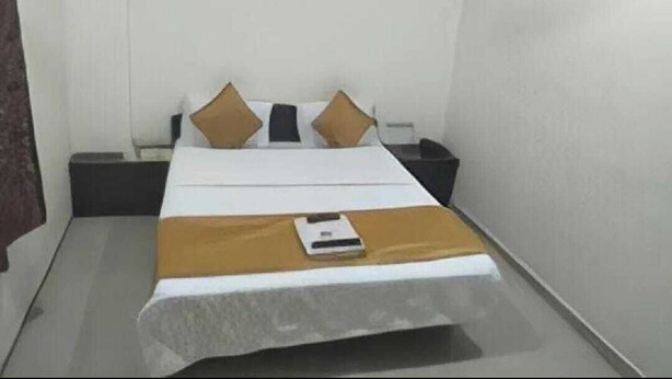 A hotel room with a bed, a nightstand, and a bedside table. - Hotel Silver Inn - Naroda (Ahmedabad)
