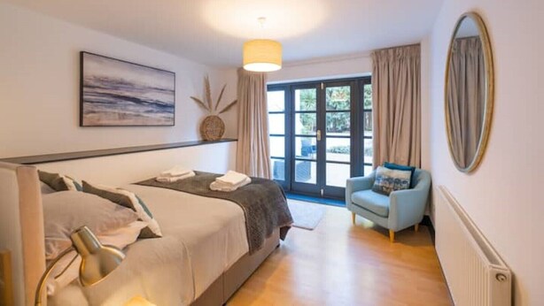 Ein Schlafzimmer mit Bett, Stuhl, großem Fenster und einem Bild an der Wand.