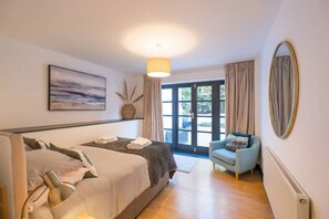 A bedroom with a bed, a chair, a large window, and a painting on the wall.