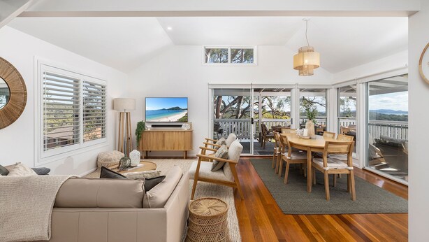 A spacious living area with a large TV, comfortable seating, and a balcony with a view. - Cabane Sur Mer – views of Shoal Bay (Shoal Bay)