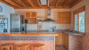 A kitchen with a central island, wooden stools, a stainless steel refrigerator, and a window with a view. - Rural House on the Tropical Coast with Salt Pool (Salobreña)