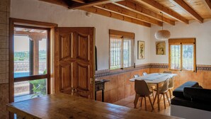 A dining area with a wooden table and chairs, a wooden ceiling, and windows with blinds. - Rural House on the Tropical Coast with Salt Pool (Salobreña)