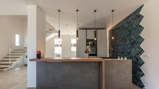 A modern kitchen with a central island, pendant lighting, and a zigzag patterned backsplash. - Villa Alla Baia dei Sette Emiri by Wonderful Italy (Cefalù)