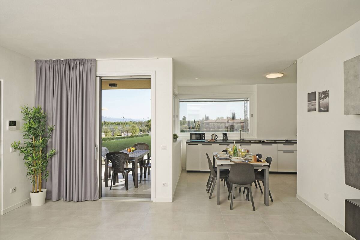A modern kitchen with a dining area, large windows, and a view of the outdoors.