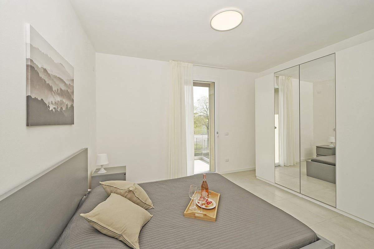 A modern bedroom with a bed, bedside table, and a large mirror.