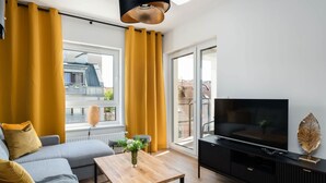 Un salon moderne avec un canapé, une table basse, un téléviseur et des rideaux jaunes.