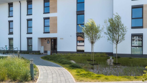 A modern building with a flat roof, large windows, and a paved entrance area with a pathway. - Elegant Apartment in Gdynia | Balcony and Private Parking (Gdynia)