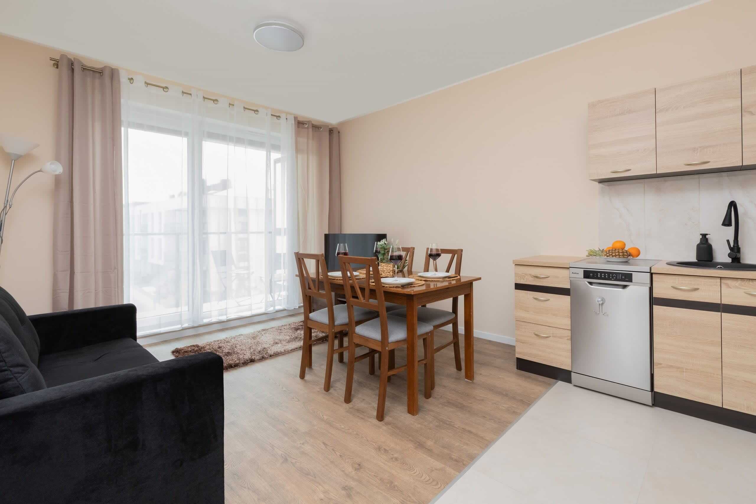 Una cucina moderna con mobili in legno, una lavastoviglie e un'area pranzo con tavolo e sedie.
