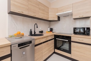 Eine moderne Küche mit Holzausstattung, Geschirrspüler, Spüle, Mikrowelle und Kaffeemaschine.