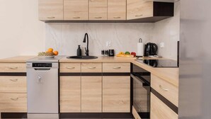 A modern kitchen with wooden cabinets, a dishwasher, a sink, and a coffee maker. - Elegant Apartment in Gdynia | Balcony and Private Parking (Gdynia)