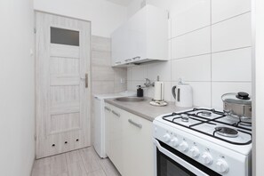 A compact kitchen with a white stove, sink, and cabinets.