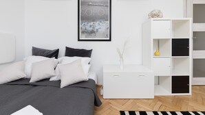Une chambre à coucher moderne avec un lit, des tables de chevet blanches, un tableau encadré et une étagère blanche.