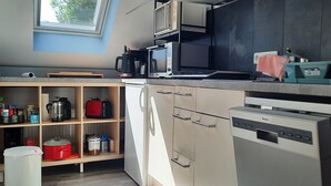 A modern kitchen with built-in appliances, a coffee maker, and storage shelves. - Charming guest house by the lake<br> (Bad Saarow)