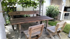 A wooden outdoor table with benches, surrounded by greenery and a garden. - Charming guest house by the lake<br> (Bad Saarow)