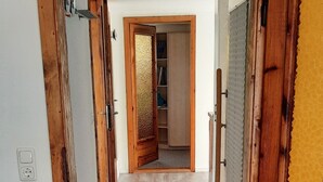A hallway with wooden doors, a patterned rug, and a grey carpet. - Charming guest house by the lake<br> (Bad Saarow)
