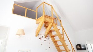 A wooden loft bed with a ladder, a wall-mounted TV, and a decorative hanging ornament. - Refúgio no Campo. A tranquilidade tão próxima da cidade, no coração do Alentejo. (Évora)