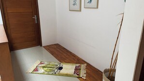 Un couloir avec une porte en bois, un tapis à motifs et un petit panier.