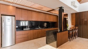 Une cuisine moderne avec des meubles en bois, un plan de travail noir et un réfrigérateur en acier inoxydable.