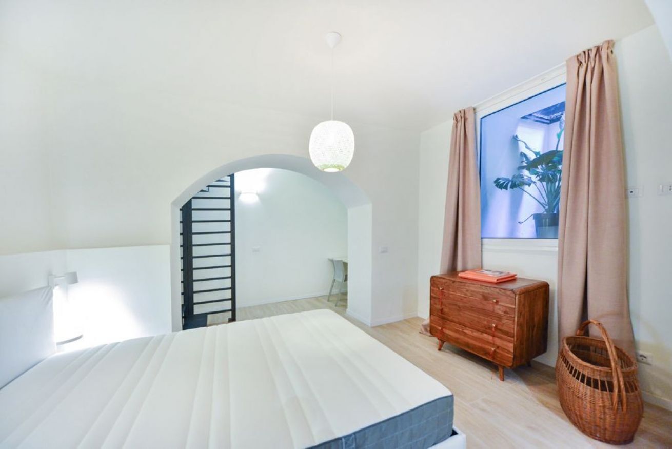 Une chambre à coucher comprenant un lit, une commode, une fenêtre avec des rideaux et un escalier.