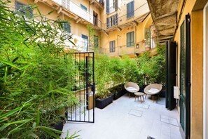 A courtyard with potted plants, a gate, and two wicker chairs. - BRERA-CENTRO New apartment with A/C ★★★★★ (Milano)