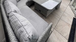 A wicker sofa with cushions, a small table, and a stone wall in a patio area. - Chic & Characteristic 2BD House - Irishtown (Dublin)