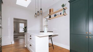 A modern kitchen with a central island, wooden shelves above, and a green cabinet to the right. - Chic & Characteristic 2BD House - Irishtown (Dublin)