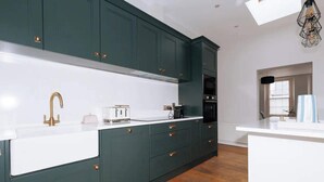 A modern kitchen with dark green cabinets, white countertops, and gold fixtures. - Chic & Characteristic 2BD House - Irishtown (Dublin)