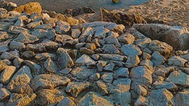 En stenet strand med en lille vandkanal.