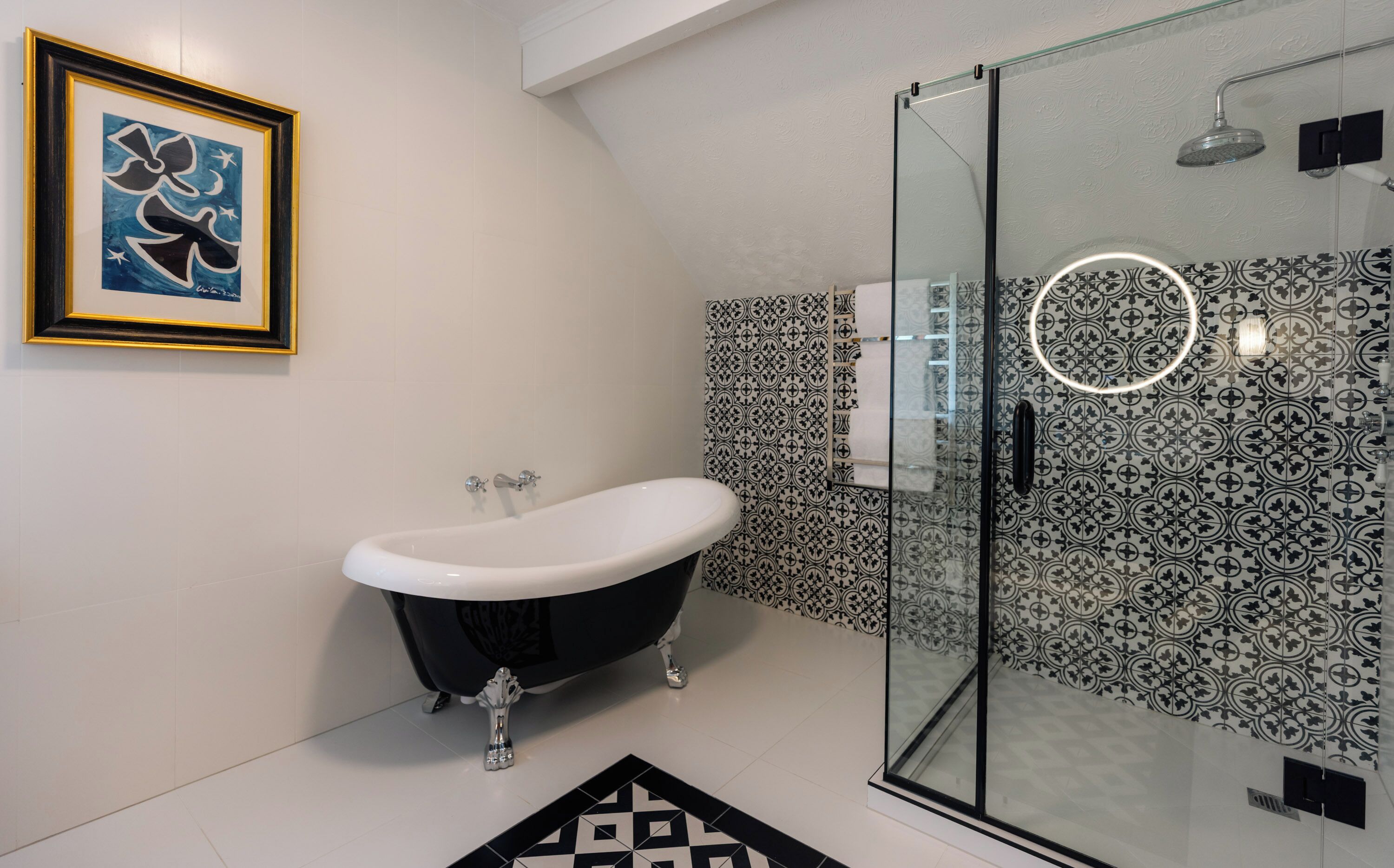 A modern bathroom with a freestanding bathtub, a glass-enclosed shower, and patterned tiles.