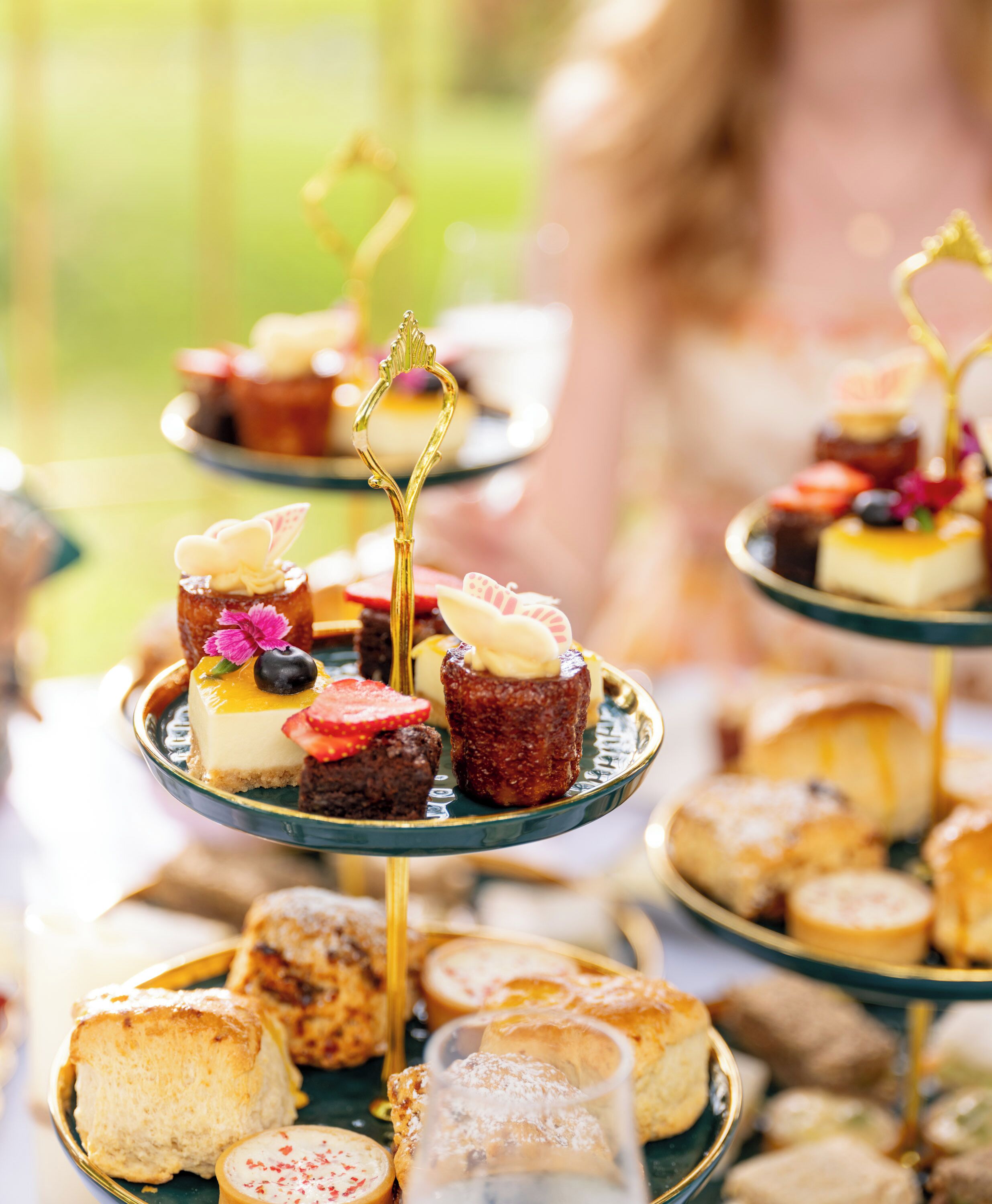 A multi-tiered dessert display with various pastries and cakes, including a cheesecake and a chocolate dessert, on a glass stand.